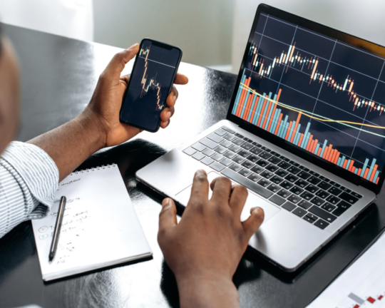 man on laptop looking at dynamic charts and on phone