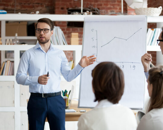 man showing upward trending graph to colleagues